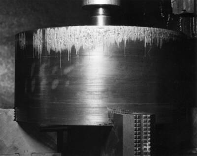 Scoring of the leading side of generator break piston #1 due to its tilting during jacking of the rotor. Top of piston is in lathe chuck--leather is removed from the bottom of piston. Unit L-1, Grand Coulee Power Plant