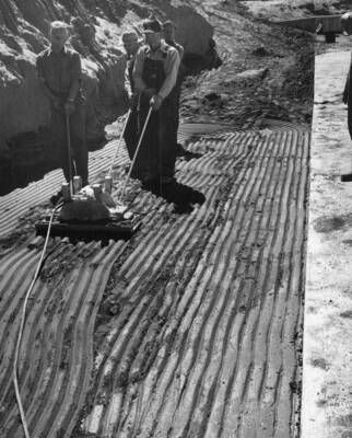 Columbia Basin Project, Irrigation Division, West Canal, Specifications 1286, Utah Construction Co., and Winston Bros. Co., Contractor. Using a Jackson electric vibrator to place compacted backfill at the lateral turnout, Station 163+25. The material being compacted is sent with very little gravel. The vibrator did not work satisfactorily in this particular material.