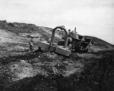 Columbia Basin Project, Irrigation Division, Specifications No. 2541, Schedule No. 2, Earthwork, Concrete Lining and Structures, Station 734+85 to Station 1229+74, West Canal. Contractor: Morrison-Knudsen Company, Inc. LaPlant-Choate rooter pulled by D-8 caterpillar tractor through cemented gravel at about Sta. 785. Only two outside ripper teeth are being used. Note difference in penetration of teeth, indicating varying hardness of deposit. West Canal located between Soap Lake, Washington and Winchester, Washington. Harold Foss, photographer.