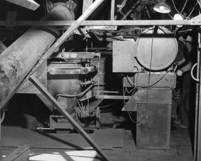 Columbia Basin Project--Irrigation Division. West Canal and East Low Canal--Specifications 1286 and 1422. View showing weighing equipment at Adco batching plant. Back of housing for cement scale dial and recorder tape are shown at right foreground. Portion of aggregate scale dial may be seen in right background. At left is screw conveyor from cement silo to cement weighing hopper in center of picture. Behind this hopper is the aggregate weighing hopper. H.E. Foss, photographer.