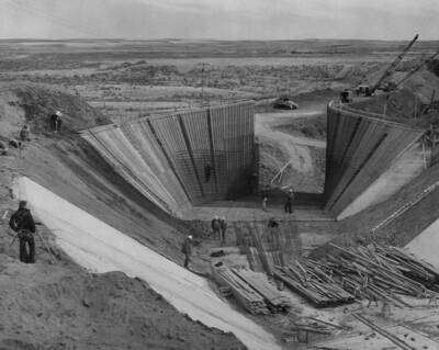 Columbia Basin Project, Irrigation Division, West Canal, Specifications No. 1286--Utah Construction Co. and Winston Bros. Co., contractor. Open outlet transition of Dry Coulee Siphon No. 2 showing back forms. Transition warps from vertical with a 25-foot bottom to a light slope with a 38-foot bottom on a 40 degree curve. Openings in the forms are for buttresses. Canal lining shows in the foreground. H.E. Foss, photographer.