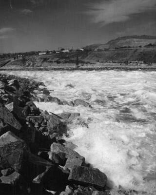 This view, looking downstream, shows the recently placed riprap along the left bank of the Columbia River with the surge from the stream coming in. See also picture 19286-3 which shows the surge receded.