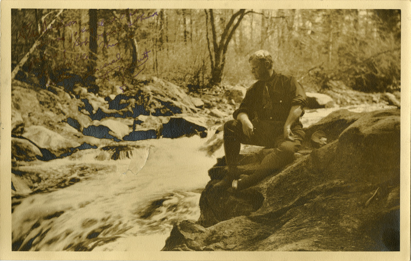 Sepia colored photo of Abraham Merritt sitting on rocks next to a river with an inscription from Merrit to Dodson.