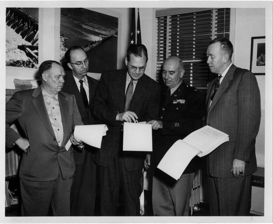 Group who worked the hardest for the project. Note on back: " A public hearing was held in Orofino on the project November 20, 1952. Here is a photo of those who worked hardest for the project. Left to right: Bill Erickson (now deceased); Robert Werner, publisher of the Clearwater Tribune, Orofino; A.B. Curtis (the guy that gets all the blame, and the Mayor of Orofino); Col. Tom Tandy, the District Engineer of Corps of Engineers (at the time), Walla Walla (now deceased); and U.S. Judge Roy McNichols (then an attorney at Orofino, now in Boise). Photo made in Tandy's office in Walla Walla where many sessions were held on the project. Photo made a few days prior to the November 20th meeting. (A.B. Curtis - 1976)"
