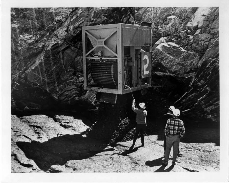 First bucket of concrete by Dravo Corp., the general contractors. Note on back: "J.L. Wixson, project manager for Dworshak Dam Constructors, pulls the cord and releases the first bucket of concrete in Dworshak Dam. The big bucket holds 8 cubic yards of concrete. (Note to editors: This picture was shot shortly in advance of official "first bucket" ceremony.) From Duane L. Cronk & Associates, 100 Bush St., San Francisco 94104  For:  Dravo Corporation, 225 108th N.E., Bellevue, Washington 98004"
