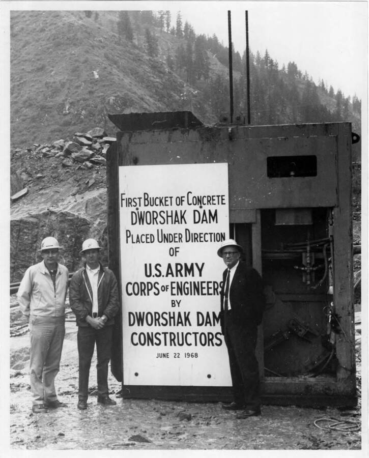 The first bucket of concrete was placed at the dam on June 22. Note on back: "" Left to right: Ed Hershberger, project engineer for the contractor; Ron Maxwell, assistant supt. of the job and J.L. Whitey Wixson, the supt. of construction for the Dravo Corp.""