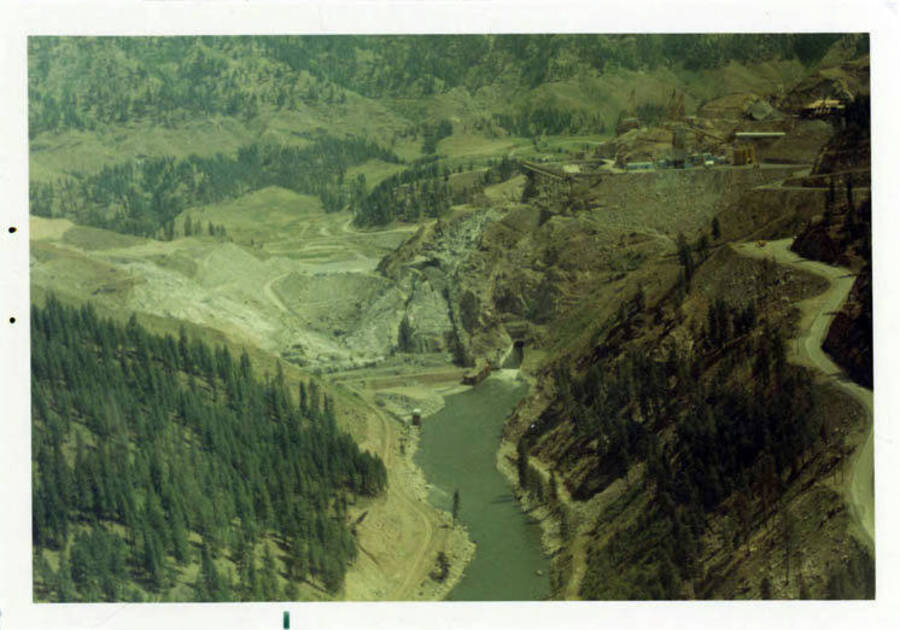Aerial view showing the very start of laying concrete on the base of the dam.  Also is seen the mouth of the diversion tunnel.