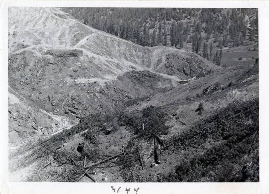 Photograph of clearing work at the site.  A machine can be seen going up the steep hillside.  The little piles of refuse will be burned.  First all merchantable timber was removed.
