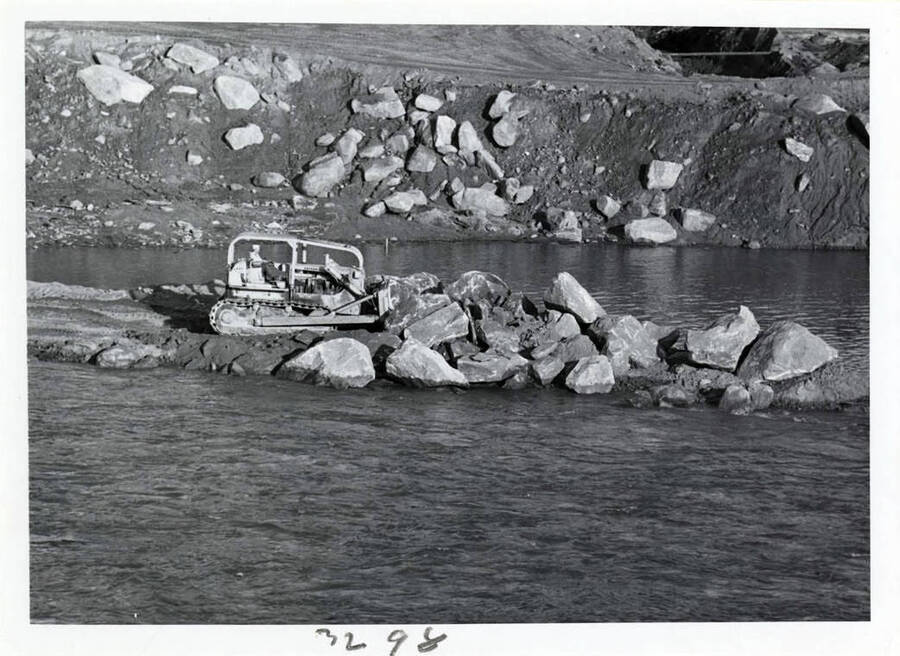 Photograph showing the coffer dam construction.  This big rock being put in is base.
