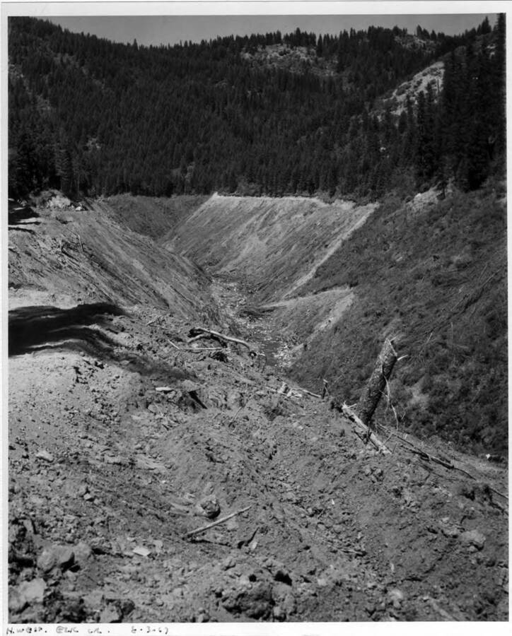 Land clearing operations in the Elk Creek area about 15 miles upstream. Note on back: ""The contractor here had to clean up everything and the work was hard to get to, isolated in some places. You will see small roads built around the top of the clearing - this is one of the things we laid down for access in case of fire on the job (A.B. Curtis)""