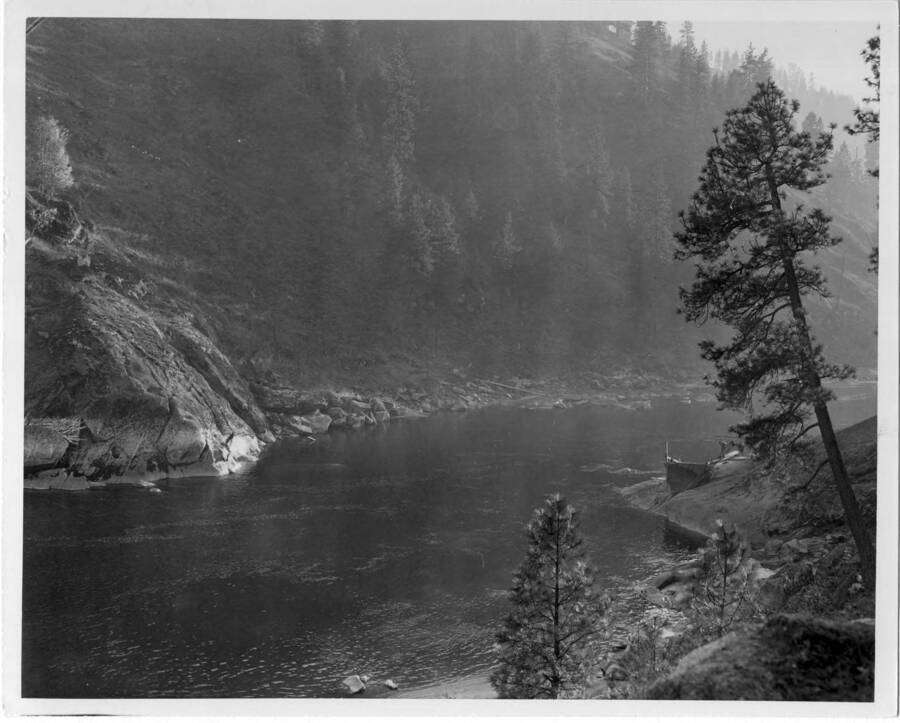 This place is called Boom Rock or better known as Little Canyon - on N. Fk. of Clearwater River. This will be location of Dent bridge. Note on back: "" Upstream from the dam we planned a bridge crossing of the pool and later you will see this bridge. Here the men are testing the bedrock and support to see if it is good enough to hand a high bridge to. The bridge will be 610 ft. above the river bottom. From this you will be able to see what the country looked like before the lake. Of course, this will never be seen in our lifetime unless somebody blasts the dam out! This place is called Boom Rock or better known as Little Canyon on the North Fork of Clearwater River. Location of Dent Bridge. (A.B. Curtis)""
