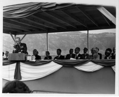 Gen. Hyzer speaks at the ground-breaking program. Note on back: "Left to right: Lt. Gov. William E. Drevlow; Senator Len B. Jordan; Mrs. Jordan; Jack Carter (one of the contractors); Master of Ceremonies A.B. Curtis, Mayor of Orofino; Don Basgen, and Col. McElwee.""