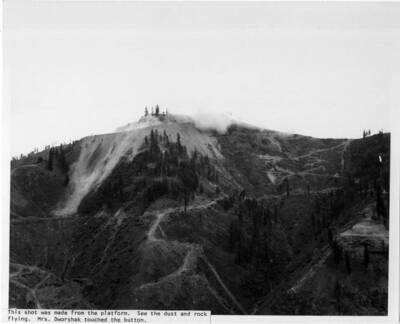 At the program a dynamite shot was made to signify that a start had been made. Note on image: "This shot was made from the platform. See the dust and rock flying. Mrs. Dworshak touched the button."