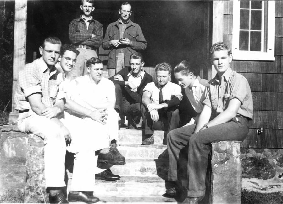 Cabin #3, l to r: J. Bush, B. Naiman, A. Nelson, L. Richards, K. Davis, L. Hayes, C. Wellner, V. Kline, D. Hendrickson. A note on back reads: Dinny: Therse are some of the fellows working at the Priest River Station. My boss, Ken Davis, is the nearest fellow standing to me. Did you ever see such a glum appearing bunch?"