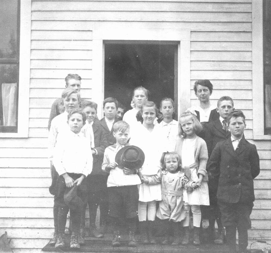 Caption titled: "School where Margaret attended 1st and 2nd grade (in 1 year) and part of 3rd until the famliy moved to Missoula, Mont.  Margaret walked along a forest rail and county roads, attended by her dog Shep, about a mile"  The school house was located on the north side of the Forest, along the East River flat.  Margaret is on the right side, first row."
