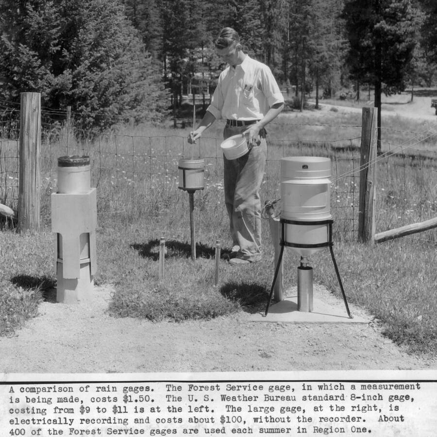 A comparison of raingages. The Forest Service gagem in which a measurement is being made, costs $1.50. The U.S. Weather Bureau standard 8-inch gage, costing from $9 to $11 is at the left. The large gage, at the right is electrically recording and costs about $100, without the recorder. About 400 of the Forest Service gages are used each summer in Region One. Pictured is G. Lloyd Hayes.
