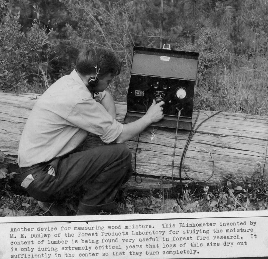 Another device for measuring wood moisture. This Blinkometer invented by M.E. Dunlap of the Forest Products Laboratory for studying the moisture content of lumber is being found very useful in forest fire research. It is only during extremely critical years that logs of this size dry out sufficiently in the center so that they burn completely. Pictured is George Jemison.