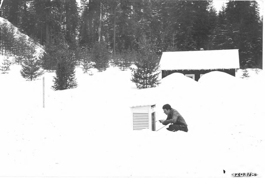 Back of photo reads: "Temp. No. 182  View of the weather station at Deception Creek on March 26, 1936.  Note snow stick on the left-hand side of picture. Shop is hidden behind the two snow piles."
