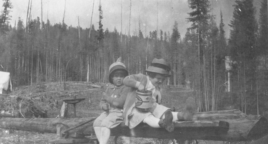 Caption titled: "Priscilla Brewster and Margaret Larsen.  The wheel on this log provided hours of play". Pricilla was the daughter of Ann and Donald Brewster. The Brewsters left Priest River Experimental Station in 1917.
