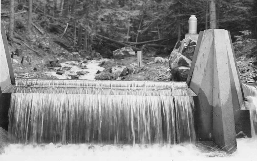 Back of photo reads: "Benton Creek gaging dam during spring runoff.  Flow or discharge = 4.46 sec. ft. Depth of water over crest of weir #2 (to the right) = 0.883 ft. Depth of water over weir #1 (main weir in center of picture) = 0.133 ft. April 15, 1940 DGM 40-17"
