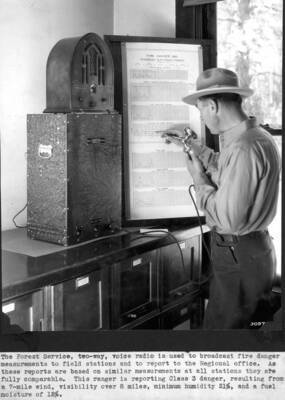 The Forest Service, two-way voice radio is used to broadcast fire danger measurements to field stations and to report to the Regional office. As these reports are based on similar measurements at all stations they are fully comparable. This ranger is reporting Class 3 danger, resulting from a 7-mile wind, visibility over 8 miles, minimum humidity 21%, and a fuel moisture of 12%. J.B. Thompson pictured.