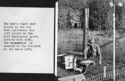 The man's right hand points to the six wood cylinders; his left points to the duff hygrograph spike, covered with duff. The anemometer is mounted on the standard at the man's left. H.T. Gisborne pictured.