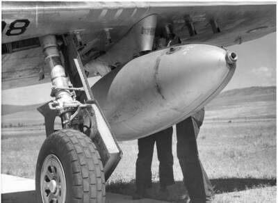 Water bomb being attached to plane for test of use of aircraft to suppress wildfires.
