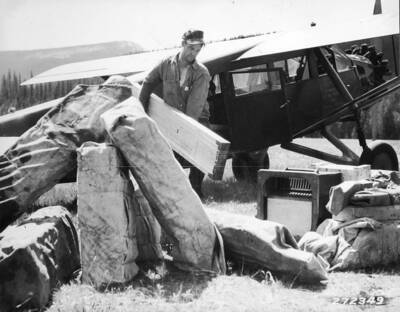 Unloading lumber and equipment from plane at Bartlett Creek Landing field.