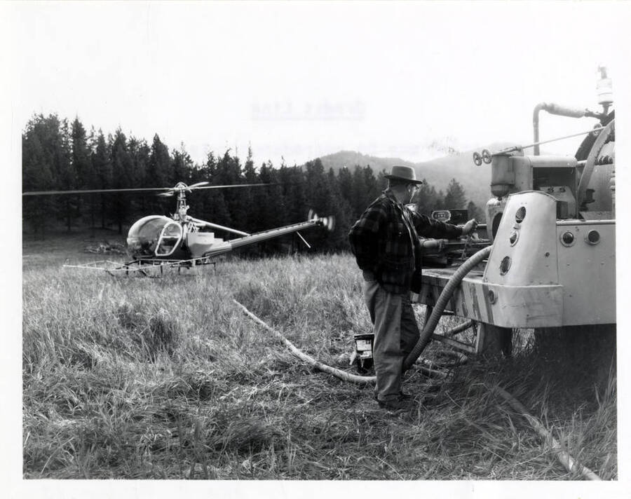A helicopter lands to refill with pesticide for aerial application.
