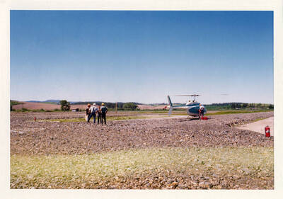 Potlatch Mill Yard: Pilot (near helicopter); mill foremen (hard hats); Grarelle, Paul (Potlatch Corp. no hat); Till, Ken (FS uniform yellow hat)