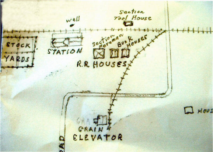 A hand-drawn map showing a railroad layout with labeled structures. The map includes "Stock Yards," "Station," "Well," "Section Tool House," "Section Foreman," "Bunk Houses," "R.R. Houses," and "Grain Elevator." A set of tracks runs diagonally across the map.