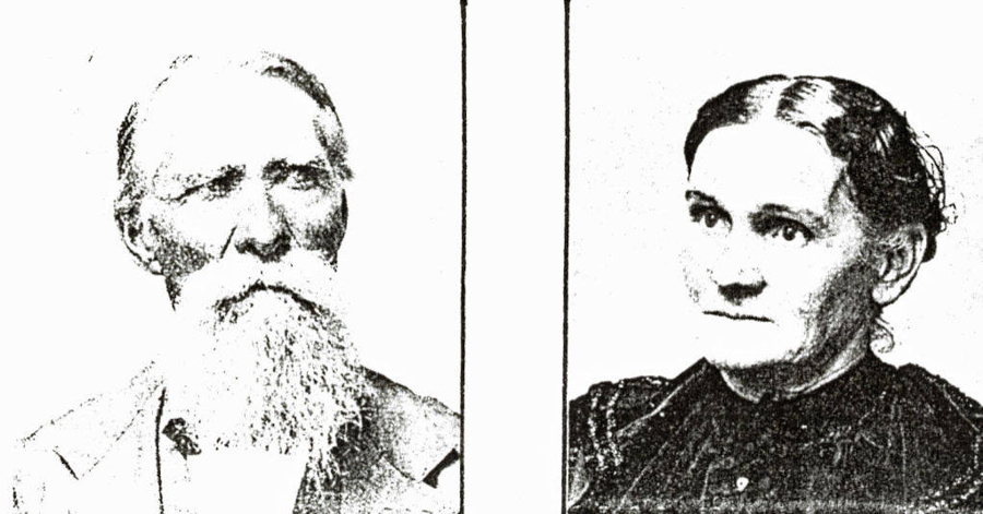 A man with a long beard, wearing a suit. Beside him, a woman with her hair pulled back, wearing a dark dress.