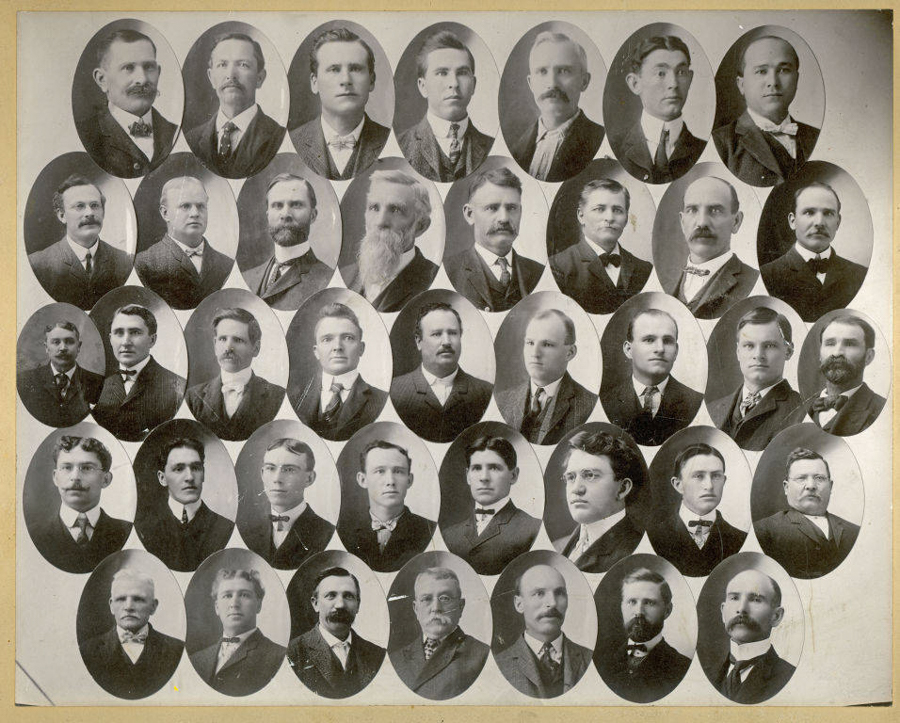 A grid of thirty-four oval portraits of men in formal attire, resembling a composite class or group photograph. Each man is wearing a suit and tie, and has a distinct hairstyle or facial hair. The portraits are arranged in five rows, and no text is present in the image.