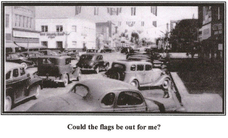 A street scene with several vintage cars parked along the road. Buildings line the street, and flags are visible hanging above. The text below reads, "Could the flags be out for me?"