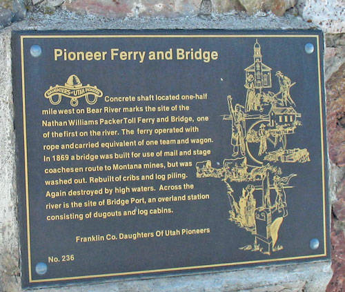 Plaque mounted on a stone surface. The text reads:

"Pioneer Ferry and Bridge

Concrete shaft located one-half mile west on Bear River marks the site of the Nathan Williams Packer Toll Ferry and Bridge, one of the first on the river. The ferry operated with rope and carted equivalent of one team and wagon. In 1869 a bridge was built for use of mail and stage coaches enroute to Montana mines, but was washed out. Rebuilt of cribs and log piling. Again destroyed by high waters. Across the river is the site of Bridge Port, an overland station consisting of dugouts and log cabins.

Franklin Co. Daughters Of Utah Pioneers

No. 236" 

An engraving shows a historic depiction of a ferry and bridge.