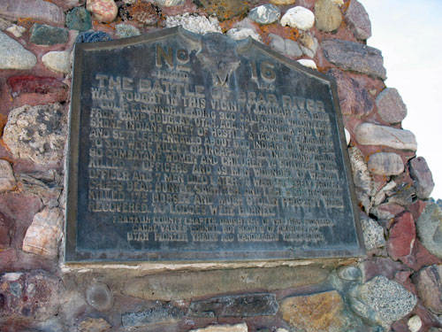 A stone structure with an attached plaque. The plaque is titled "No. 16 THE BATTLE OF PRAIRIE" and details a historical event involving the pursuit of Native Americans in 1838 by a group of soldiers. It notes that a soldier and six Native Americans were killed. The text describes how Lieutenant Wood and his company were traveling from Fort Armstrong, and includes a sentence about the aftermath, mentioning the pursuit and fatalities.