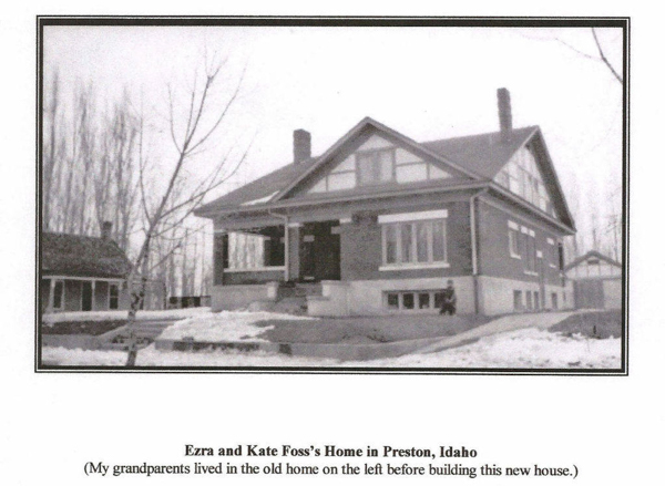 A large two-story house with a porch and multiple windows is situated on a snowy landscape. There is a smaller building to the left of the main house. A person is sitting on the steps in front of the house. Sparse trees are visible in the background. Text reads: "Ezra and Kate Foss's Home in Preston, Idaho." Below it, another line reads: "(My grandparents lived in the old home on the left before building this new house.)"