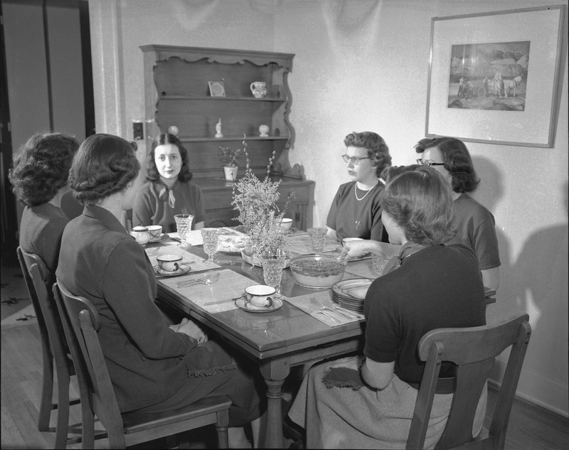 Home Economics students sitting around a set table.