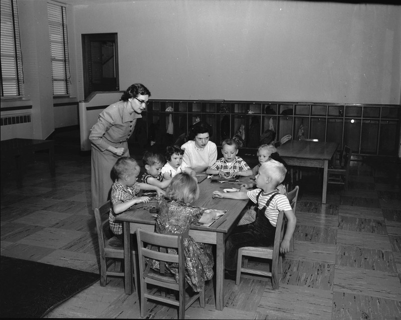 Two women looking over a group of small children.