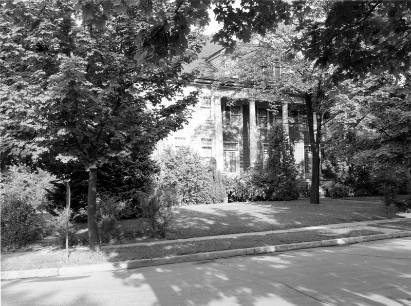 A photograph of Alpha Phi sorority house through the foliage.