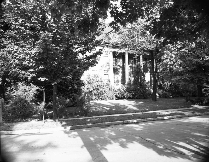 A photograph of Alpha Phi sorority house through the foliage.