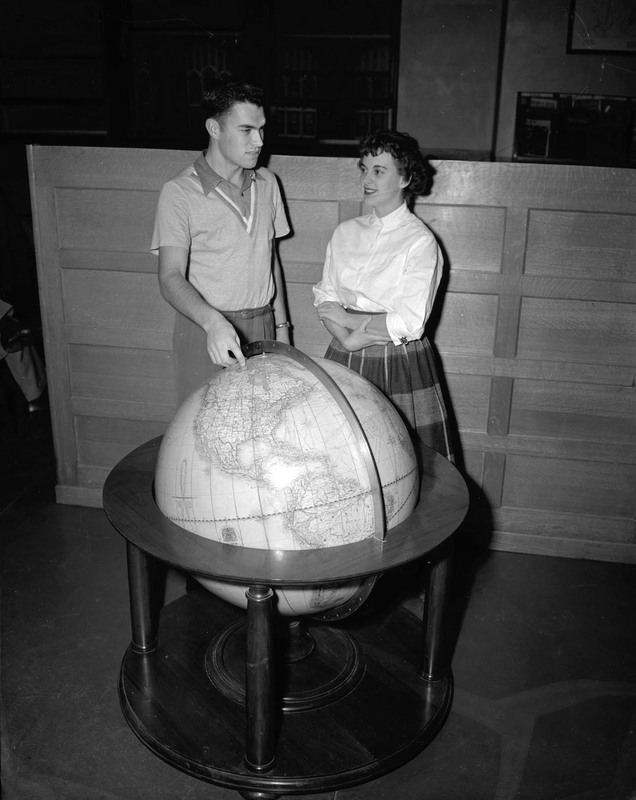 Two students looking at a large globe.