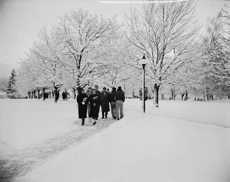 Students walking through a snowy landscape on campus.
