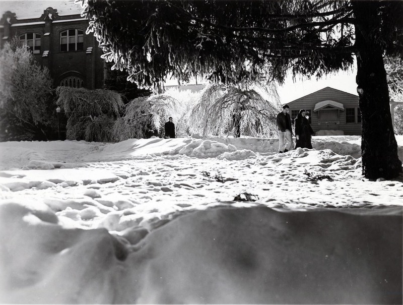 Students walk along a snowy path on University of Idaho Campus, institutional buildings can be seen in the background.