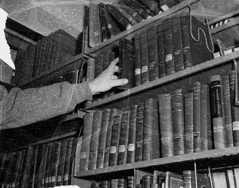 A photograph of an unidentified person grabbing a book of the shelf in the University of Idaho Library.