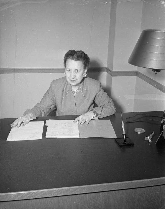 A portrait of Home Economics Professor Margaret Ritchie sitting at her desk writing on documents in front of her.