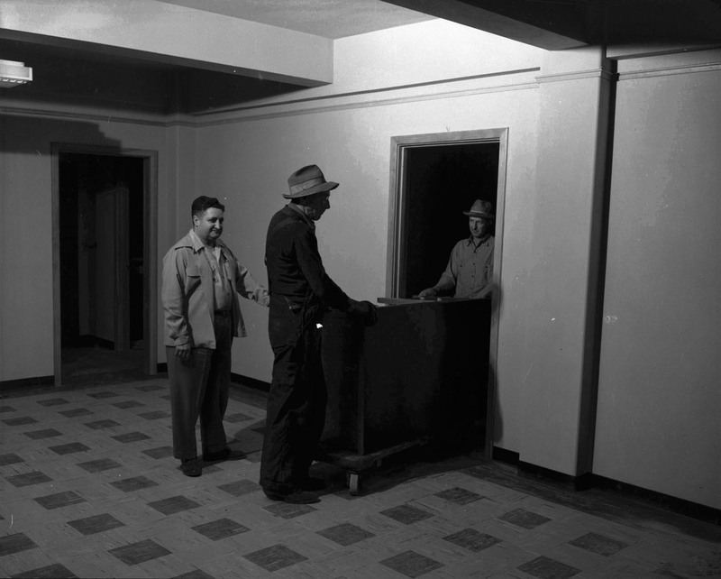 Three men moving a desk in the Student Union Building.