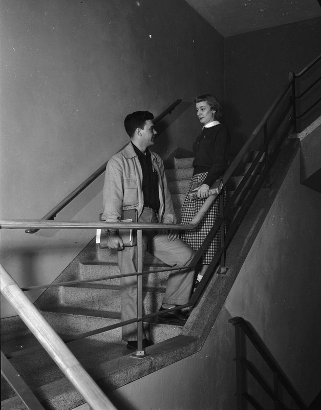 Two students socializing in the stairwell of the Student Union Building.