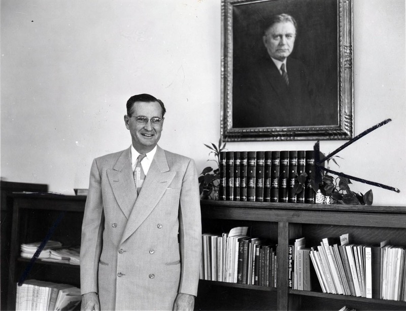 A portrait of President J.E. Buchanan standing in front of a bookshelf.