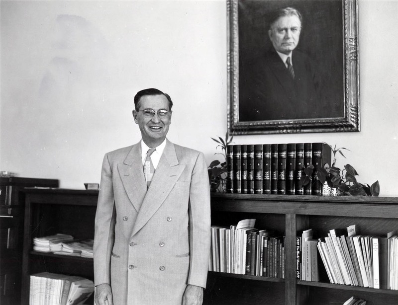 A portrait of President J.E. Buchanan standing in front of a bookshelf.